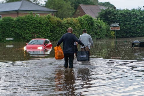 Flooding in Durham showing submerged car and people wading through water