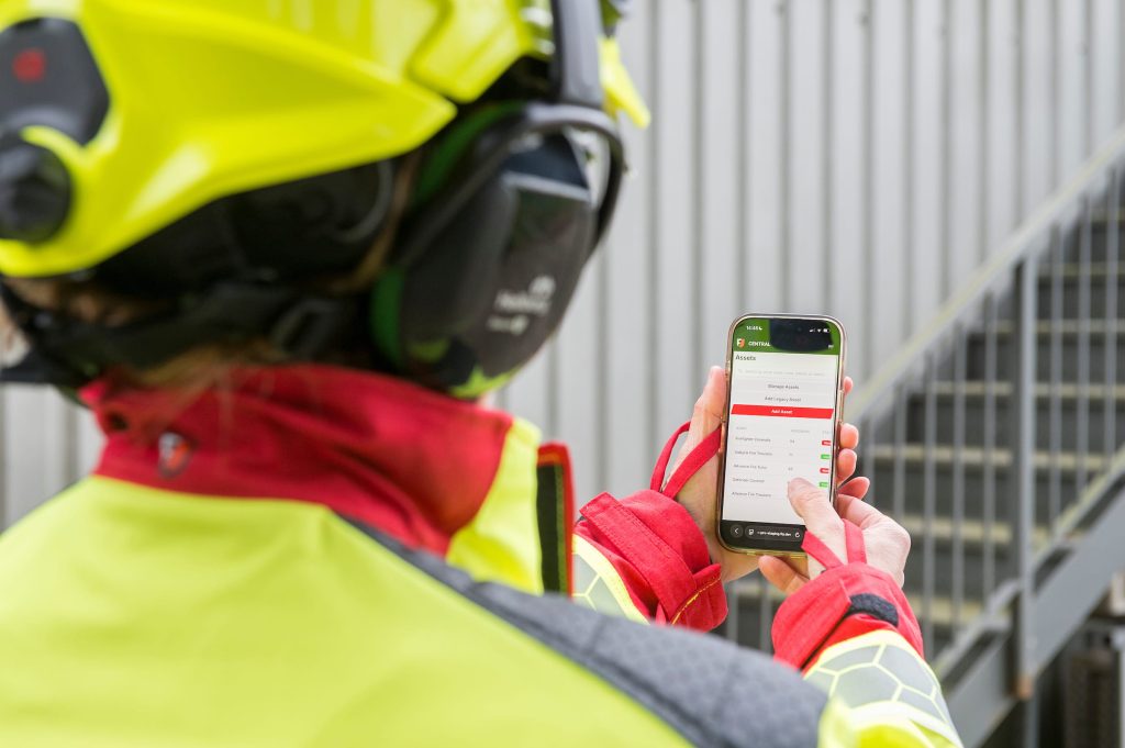 Firefighter holding mobile phone showing FlamePro app.