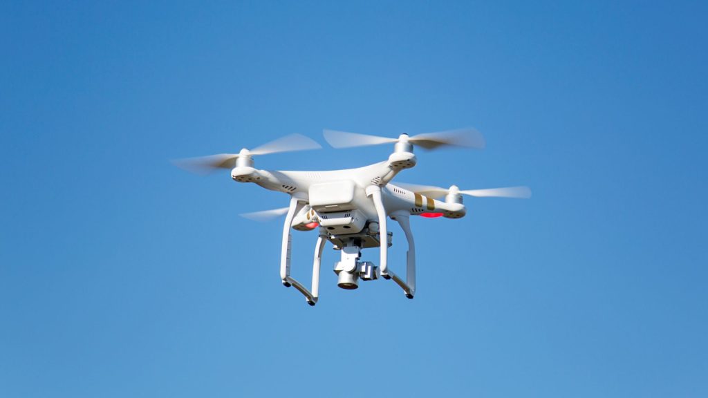 White drone hovering in the sky. Photo credit: Canva Teams.